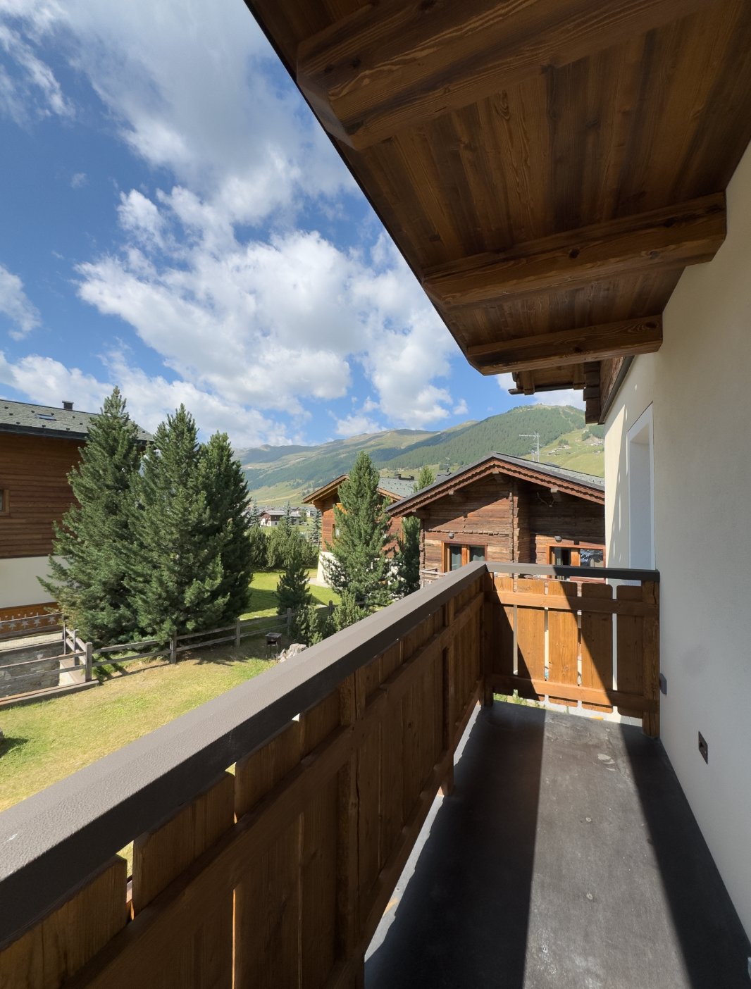Il balcone in legno di un appartamento, affacciato sui tetti e sulle montagne di Livigno